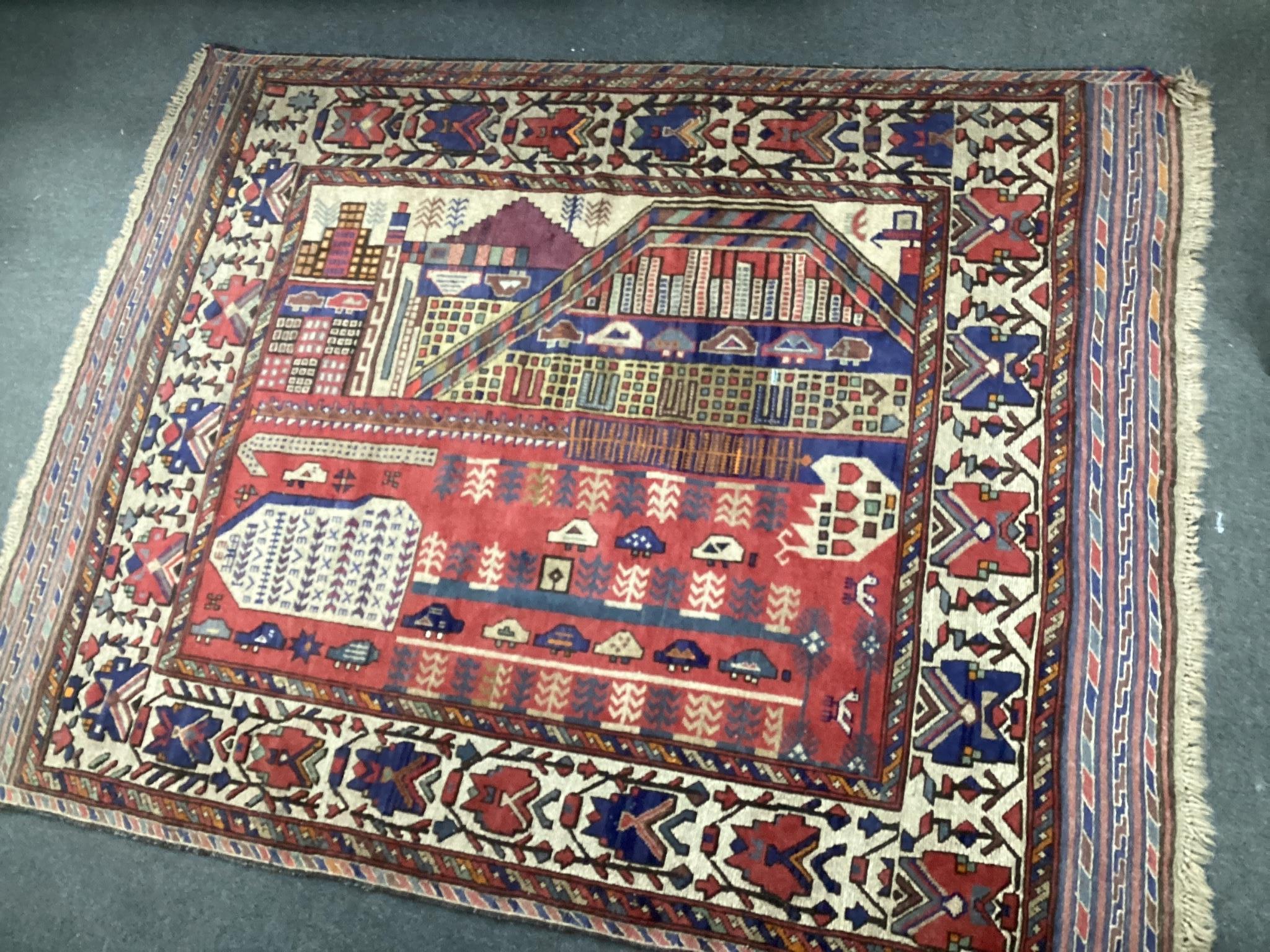 A mid 20th century Afghan red ground pictorial rug woven with an abstract city scene, 180cm x 140cm.